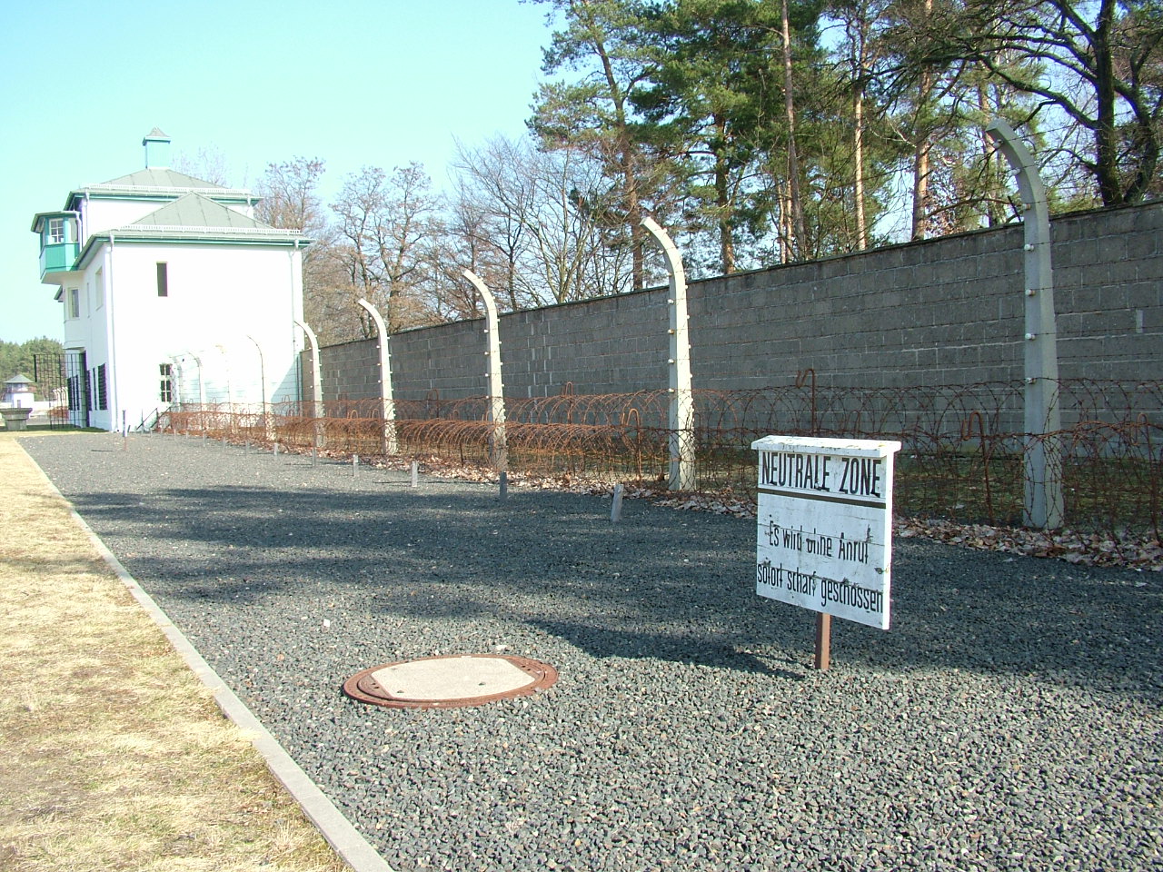 35 kilometers of Berlin: the main gate and fence of the Sachsenhausen concentration camp. The sign reads: “Shots will be fired without warning”.