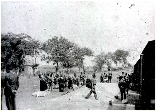 Deportation of the Soldvadkert Jews. In front of the cattle cars are armed gendarmes.  (Photo: Hungarian National Museum)