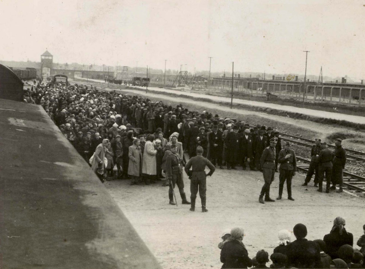 Before selection: Hungarian Jewish men and women lined up in separate rows of five. In the center is Dr. Mengele with a cigarette in his hand. (Photo: Hungarian National Museum/YadVashem Archives)